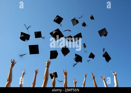 Graduation Caps Thrown in the Air on blue sky Stock Photo