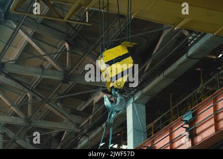 Hook of overhead beam crane in factory close-up. Stock Photo