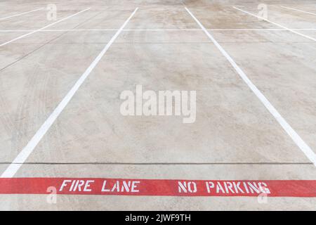 Fire lane no parking marking on the road of a parking lot, red line with white inscription on the asphalt, car parking is prohibited Stock Photo