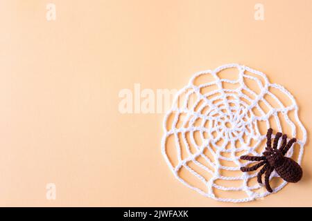 Halloween concept. Knitted black spider and white web on an orange background with space for text, flat lay Stock Photo