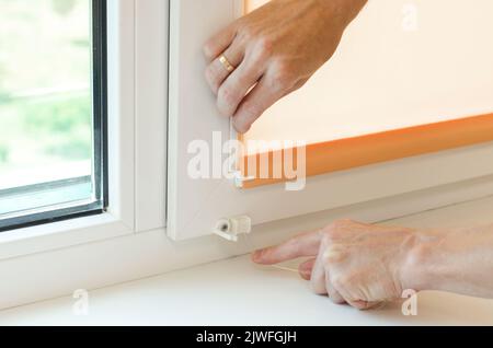 Assembly of roller blinds. Hands are assembling roller blinds, close-up Stock Photo