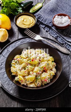 delicious shout hallelujah potato salad with pickles, celery, eggs, jalapeno and mayonnaise dressing in black bowl, american cuisine, vertical view Stock Photo