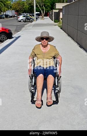 Elderly woman using wheelchair on sidewalk, Rio Stock Photo