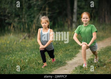 Two ten-year-old girls warming up before a jog in the park. Stock Photo