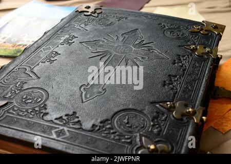 Old Bible with leather cover in black and white with engraved cross symbol for christian content Stock Photo