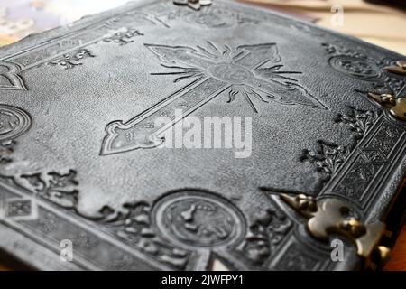 Old Bible with leather cover in black and white with engraved cross symbol for christian content Stock Photo