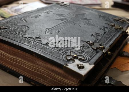 Old Bible with leather cover in black and white with engraved cross symbol for christian content Stock Photo