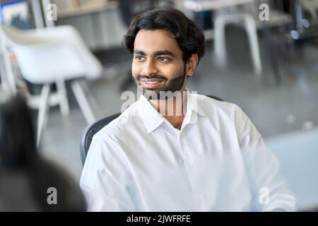 Smiling indian business man looking away thinking planning at work in office. Stock Photo