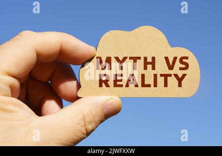 Against the background of the sky in the hands of a man, a figure of a cloud with the inscription - myth vs reality. Technology and business concept. Stock Photo