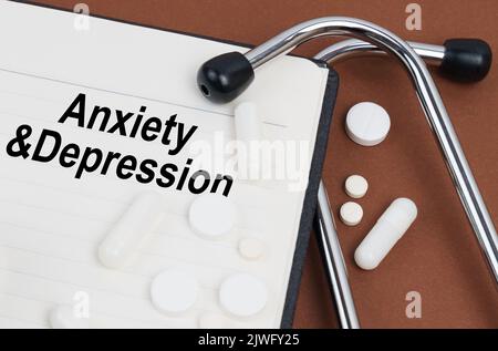 Medical concept. On a brown surface lies a stethoscope, pills and a notepad with the inscription - Anxiety and Depression Stock Photo