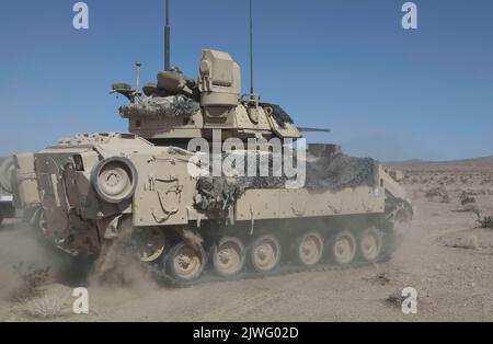 U.S. Soldiers assigned to 5th Squadron, 4th Cavalry Regiment, 2nd Armored Brigade Combat Team, 1st Infantry Division maneuver an M2 Bradley over terrain during Decisive Action Rotation 22-09 at the National Training Center, Fort Irwin, Calif., Aug. 14th, 2022 (U.S. Army photo by Pfc. Jeffrey Garland, Operations Group, National Training Center) Stock Photo