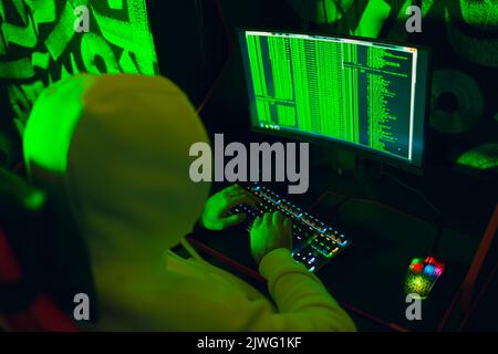 Hacker in hoodie working hacks code site on personal computer. War and cyber attack concept Stock Photo