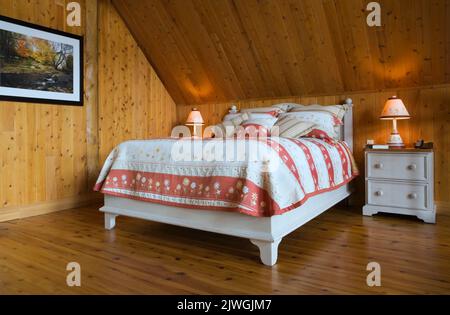 King size bed in master bedroom on upstairs floor inside handcrafted spruce log home. Stock Photo
