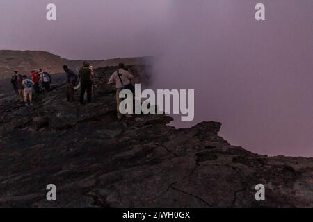 AFAR, ETHIOPIA - MARCH 26, 2019: Tourists at the edge of Erta Ale volcano crater in Afar depression, Ethiopia Stock Photo