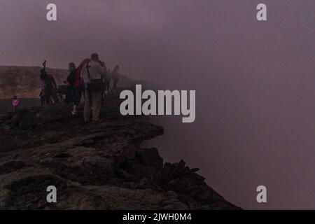 AFAR, ETHIOPIA - MARCH 26, 2019: Tourists at the edge of Erta Ale volcano crater in Afar depression, Ethiopia Stock Photo