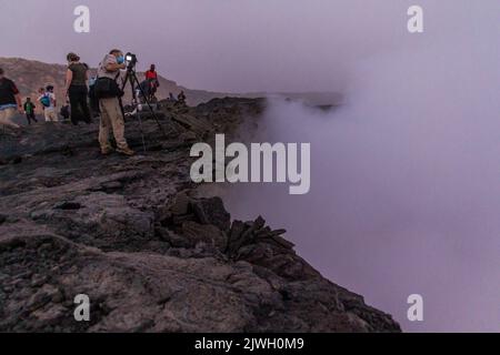 AFAR, ETHIOPIA - MARCH 26, 2019: Tourists at the edge of Erta Ale volcano crater in Afar depression, Ethiopia Stock Photo