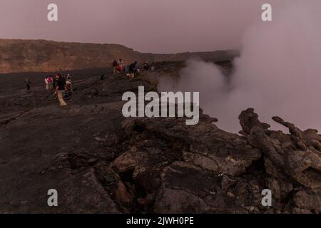 AFAR, ETHIOPIA - MARCH 26, 2019: Tourists at the edge of Erta Ale volcano crater in Afar depression, Ethiopia Stock Photo