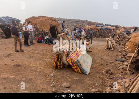 AFAR, ETHIOPIA - MARCH 26, 2019: Tourists with camels at Erta Ale volcano crater rim in Afar depression, Ethiopia Stock Photo