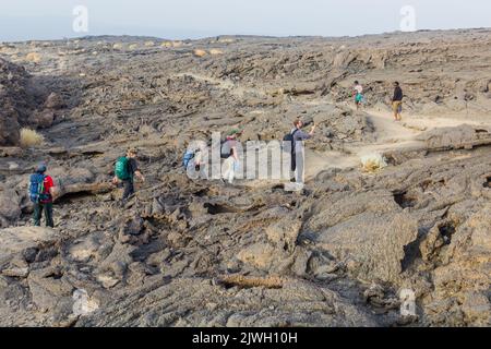 AFAR, ETHIOPIA - MARCH 26, 2019: Tourists walking across lava fields at Erta Ale volcano in Afar depression, Ethiopia Stock Photo