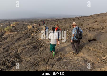 AFAR, ETHIOPIA - MARCH 26, 2019: Tourists walking across lava fields at Erta Ale volcano in Afar depression, Ethiopia Stock Photo