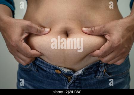 Overweight Asian woman show fat belly at office. Stock Photo