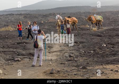 AFAR, ETHIOPIA - MARCH 26, 2019: Tourists walking across lava fields at Erta Ale volcano in Afar depression, Ethiopia Stock Photo