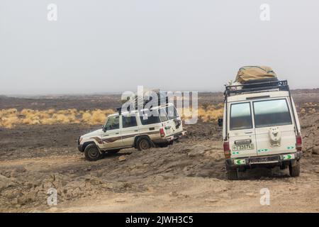 AFAR, ETHIOPIA - MARCH 26, 2019: Vehicles crossing lava fields on their way from Erta Ale volcano in Afar depression, Ethiopia Stock Photo