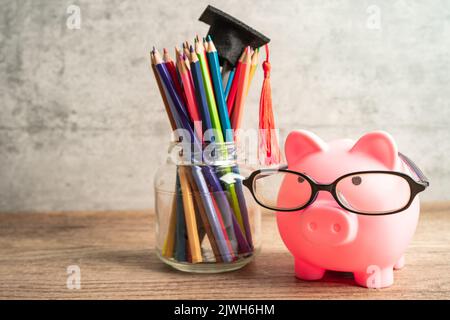 Pigging bank wearing eyeglass with colorful pencils; saving bank education concept. Stock Photo