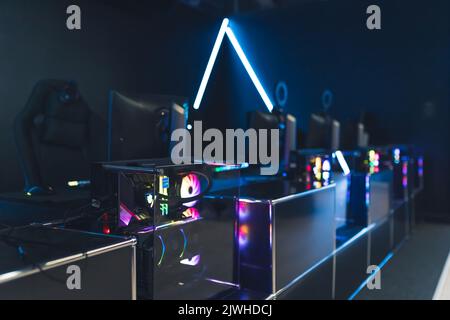 Monitors and computers in trapnsparent cases with rainbow glowing fans. Professional gaming setup. Blue neon lights. Horizontal shot. High quality photo Stock Photo