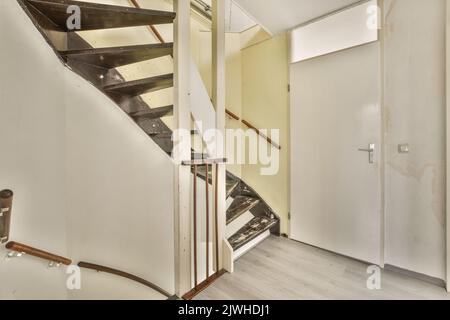 Interior of small corridor with radiator hanging on wall against stairway in daylight Stock Photo