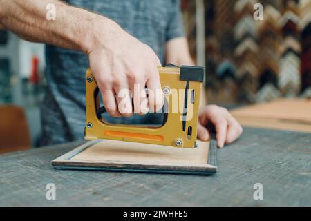 Framing Workshop. Making assembly stapler brackets baguette handmade picture frame at studio. Stock Photo