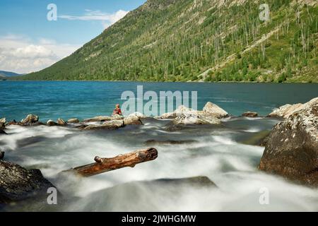 A boy seen fishing near Siberian cedar on the 'Shumy' of the Multa River in the Altai Mountains.Just four hours by plane from Moscow, and you find yourself in a completely different world: the world of majestic young mountains, wide green hilly valleys, cedar forests, turbulent rivers and glacial lakes. Altai! Stock Photo