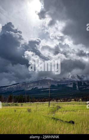 Sun bursting through the clouds above a meadow and mountains near the Jasper Airfield in Jasper National Park, Alberta Stock Photo