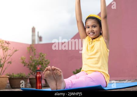 An Indian girl child practicing yoga in smiling face on yoga mat outdoors  Stock Photo - Alamy