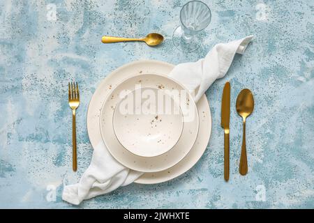 Simple table setting with plates, cutlery and glass on blue background Stock Photo