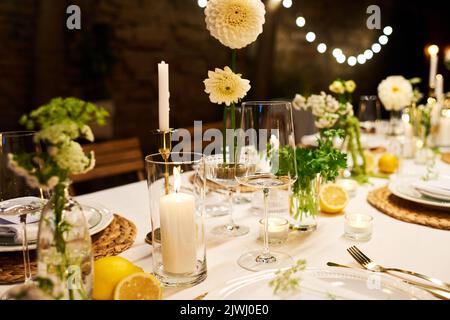 Close-up of dinner table with wineglasses, candles, dahlia flowers and other decorations prepared for wedding feast in luxurious restaurant Stock Photo