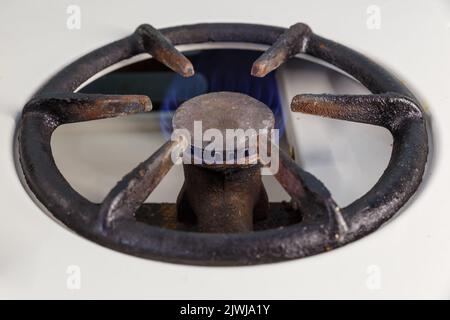 The gas burner on the stove is on and burns with a blue flame. Vintage gas burner. Stock Photo