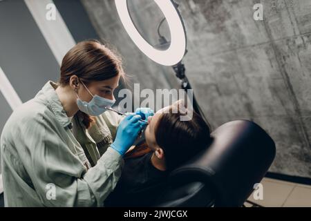 Young woman doing piercing at beauty studio salon Stock Photo