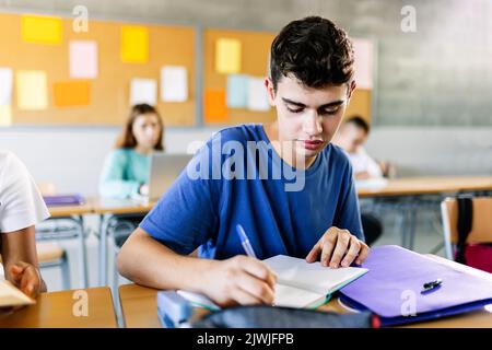 High school young student writing to notebook in class lecture Stock Photo