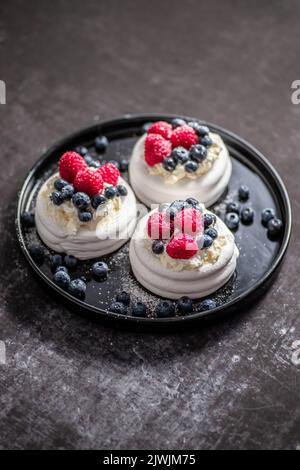 Mini Pavlova cakes topped with berries and mascarpone cheese Stock Photo