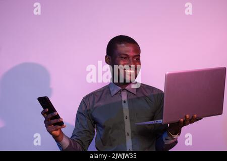 african man using a phone and laptop Stock Photo