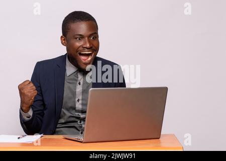 african businessman rejoices while looking at his laptop Stock Photo