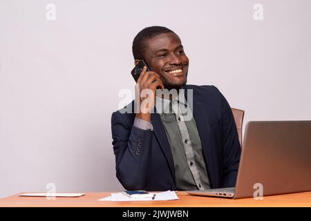 black businessman making a call while using his laptop Stock Photo