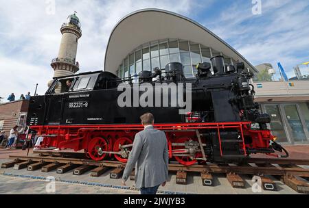 06 September 2022, Mecklenburg-Western Pomerania, Warnemünde: At the start of the Baltic resort's bridge festival, a locomotive of the 'Molli' narrow-gauge railroad stands on Stephan Jantzen Square in front of the lighthouse and the Teepott. The action is to promote the extension of the Molli line of the Mecklenburgische Bäderbahn GmbH to Warnemünde and Rerik. Photo: Bernd Wüstneck/dpa Stock Photo