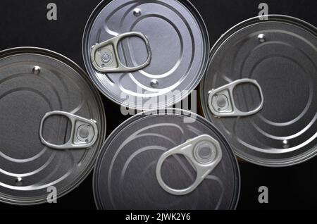 Group of tin cans shot from above showing ring pull openers on black background Stock Photo