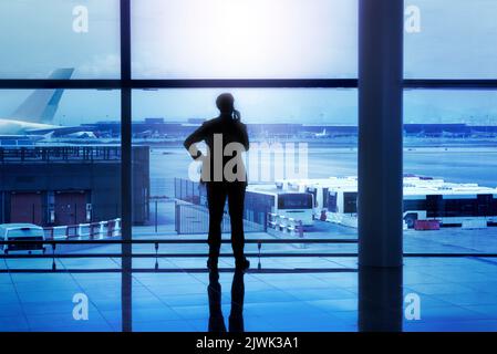 Businessman silhouette calling by phone in airport lobby in front of glass windows Stock Photo
