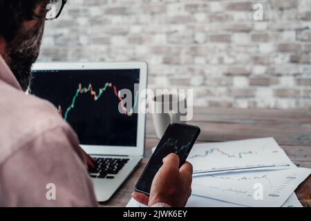 Stock and forex market business exchange with crypto currency business lifestyle. Back view of a man buying and selling stocks using laptop and mobile Stock Photo