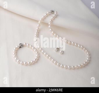 Set of pearl jewerly, beautiful bracelet, earrings and necklace display on white cloth Stock Photo