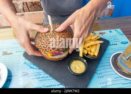 Woman eating hamburger and chips in Spanish bar Stock Photo