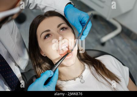 Over the shoulder view of a dental doctor treating female patient. Female having routine dental checkup at dentist. Stock Photo